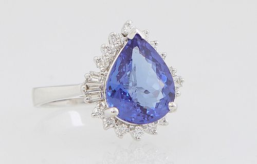 Lady's 18K White Gold Dinner Ring with a pear shaped 3.43 carat tanzanite atop a conforming border of round diamonds flanking baguette diamond mounted
