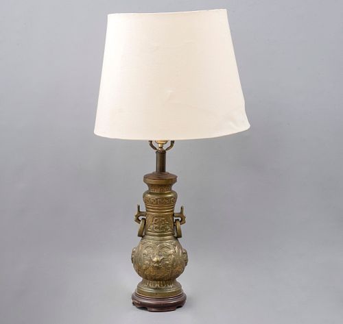 Lámpara de mesa. China, SXX. Elaborada en bronce. Con base de madera y pantalla de tela color beige. Electrificada para una luz.