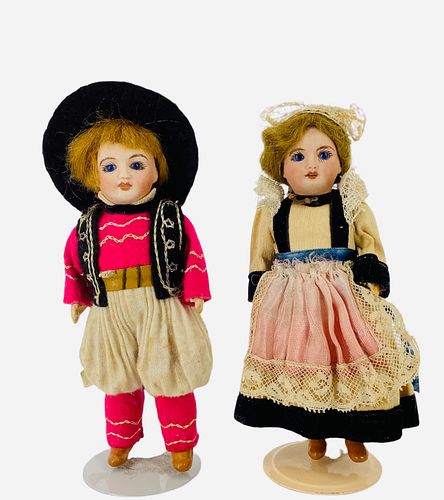 Pair UNIS bisque socket head dolls in regional costumes. Each is 5" with mohair wigs, stationary glass eyes, open mouths with teeth, on five-piece com