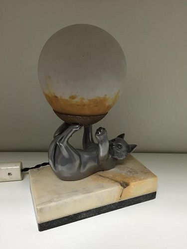 An Art Deco desk lamp, in the form of a spelter cat upon its back supporting a glass shade with its