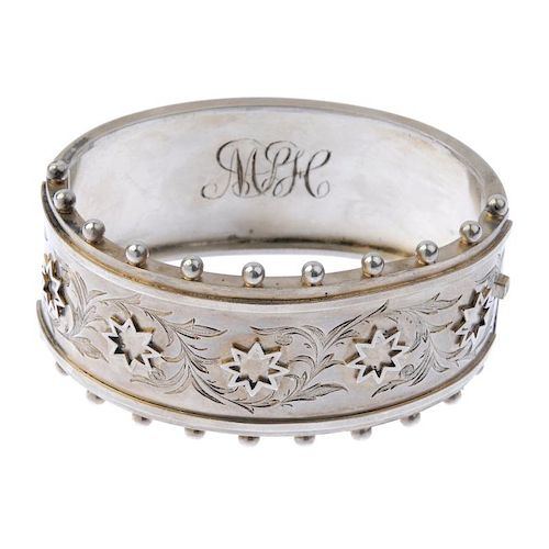 Three silver bangles and a napkin ring. To include one with applied stars and foliate engraving to t