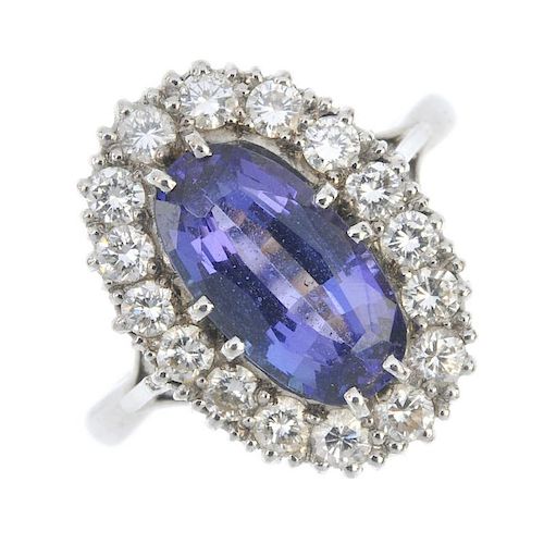 An 18ct gold tanzanite and diamond cluster ring. The oval-shape tanzanite, within a brilliant-cut di