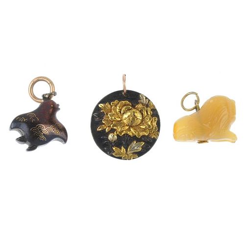 A selection of three pendants. To include a shakudo floral disc pendant, a carved agate lion pendant