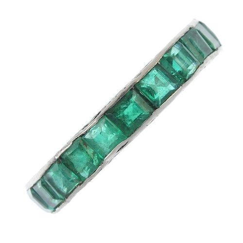 An emerald full-circle eternity ring. The square-shape emerald line, with scrolling engraved sides.