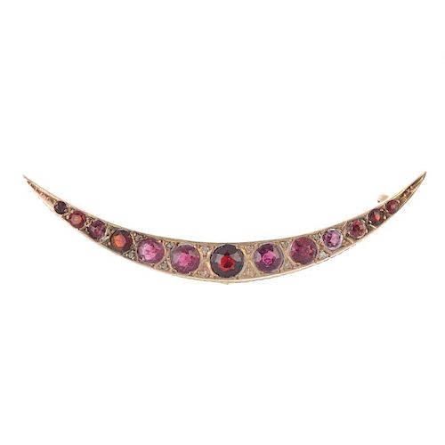 An early 20th century 9ct gold garnet crescent brooch. Set throughout with graduated circular-shape