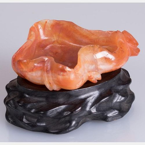 A Chinese Carved Agate Lotus Leaf Form Washer on a Carved Hardwood Stand.