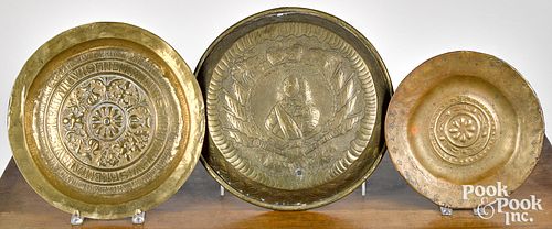 Three embossed brass alms dishes and plaques.