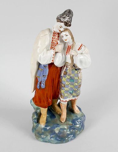 A Russian porcelain figure group, modelled as a young couple holding hands in traditional dress, blu