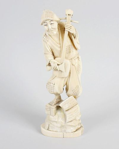 A Japanese Meiji period carved ivory okimono modelled as a musician playing a shamisen, standing upo