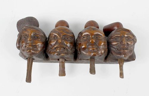 A carved figural pipe rack. Modelled as four grotesque masks each supporting a pipe, 10.75 (27.5cm)