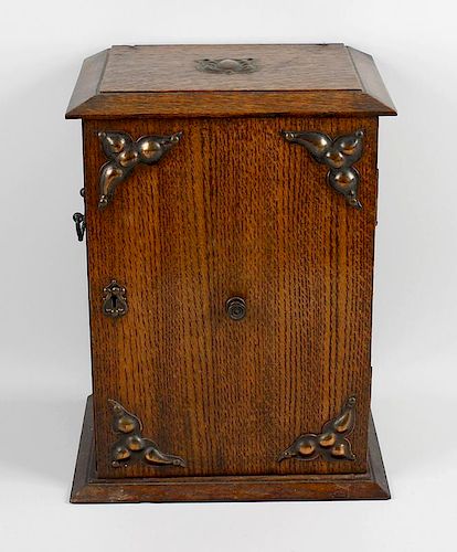 An early 20th century oak smokers cabinet. Having applied copper fittings to the exterior and single