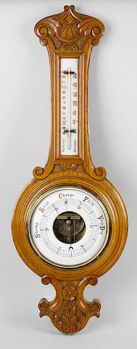 An Edwardian carved oak aneroid barometer, the 7.5 convex main dial with exposed centre reading from