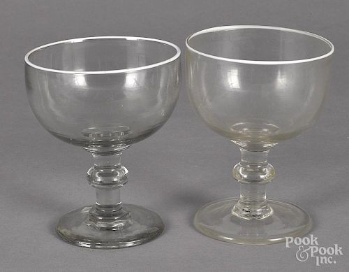 Two colorless glass footed bowls, 19th c., each with a white enameled rim