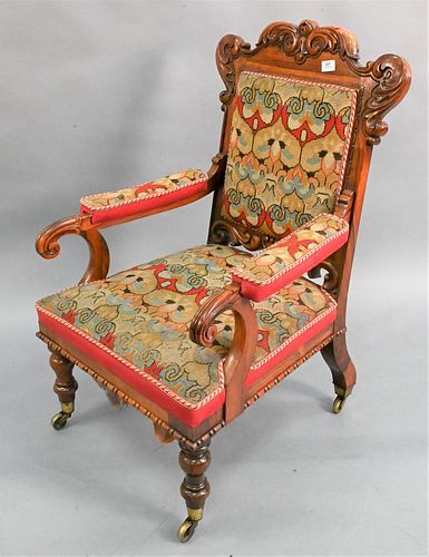 Victorian Rosewood Armchair, having carved frame and needlepoint upholstery on brass wheels, height 40 inches, width 23 inches.