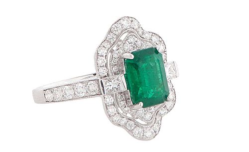 Lady's 18K White Gold Dinner Ring, with a 1.56 ct. emerald, atop a shaped border of small round diamonds flanked by diamond mounted lugs and a conform