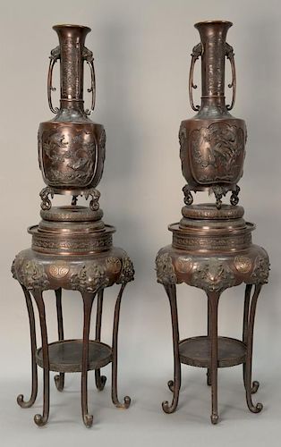 Pair of large Japanese bronze vases having relief panels of landscapes, birds, and dragons, sitting on three elephant head feet on c...
