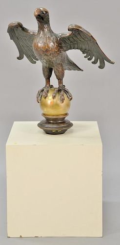 Large bronze eagle with wings spread perched on sphere set on large wood box. 
eagle and sphere: ht. 32 1/2 in.; wd. 28 1/4 in.
