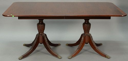 Custom mahogany double pedestal dining table with banded inlaid top on carved pedestals, each set on four downswept members ending i...
