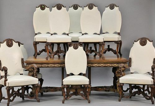 Eleven piece walnut dining room set with ten leather upholstered chairs, each with carved knight medallions, armchairs carved with f...