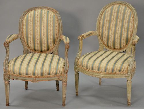 Two near matching Louis XVI style gray and white painted fauteuils having oval incurved back, fluted and scrolled arms on turned and...
