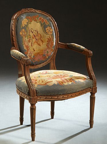 French Carved Walnut Louis XVI Fauteuil, 19th c., the canted medallion back over upholstered reeded arms and a bowed cushion seat, on turned tapered r