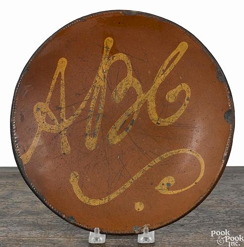 New England redware pie plate, 19th c., with yellow slip inscription ABC, 10'' dia.