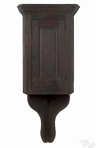 Pine hanging corner cupboard, late 18th c., with a raised panel door and old red stain, 58 1/2'' h.