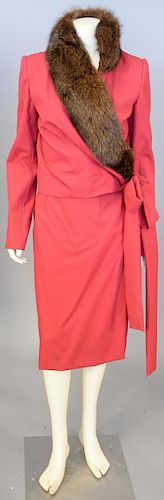 Mary McFadden, c. 1990, Skirt and jacket set of red cotton. The jacket has a wrapped front, tying on left side. The neckline is edged with brown fur, 