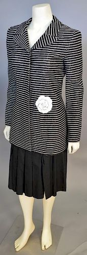 Chanel two piece suit including black and white striped long jacket with flower accent and a black pleated skirt.