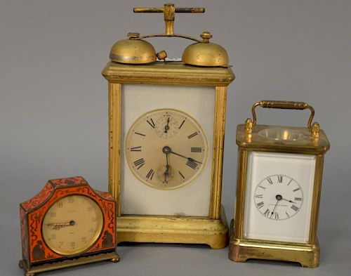 Three desk or alarm clocks to include Kienzle Day enameled clock, a brass and glass carriage clock with enameled dial, and a carriag...
