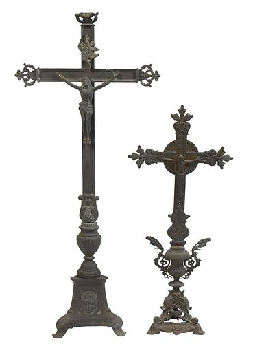 Two Large Brass Crucifixes, 19th c., the taller with an "INRI" motto over an urn support to a tripodal base with relief decoration; the smaller on an 