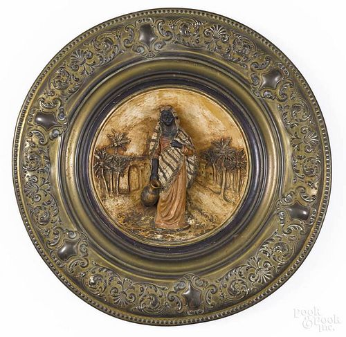 Embossed brass plaque, late 19th c., with a central ceramic roundel of a Moorish woman