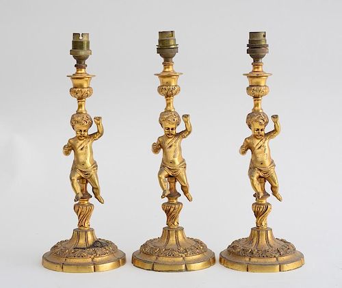 THREE NAPOLEON III STYLE GILT-METAL FIGURAL CANDLESTICKS, MOUNTED AS LAMPS