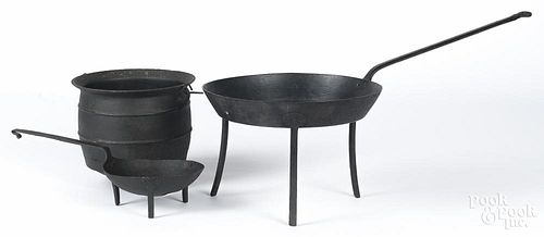 Two wrought iron skillets, together with a cauldron.