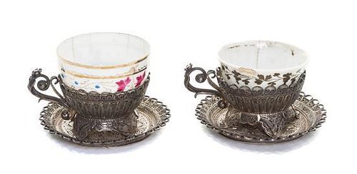 A Pair of Filigree Cups and Saucers with Porcelain Liners, Early 20th Century, the circular saucers with up-turned borders, the