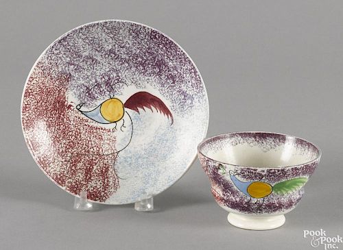 Red, blue, and purple rainbow spatter cup and saucer with peafowl decoration.