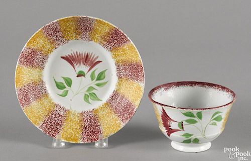 Red and yellow rainbow spatter cup and saucer with thistle decoration.