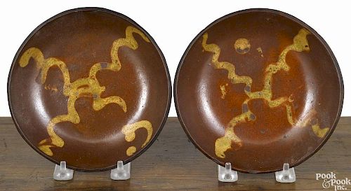 Two similar Pennsylvania redware shallow bowls, 19th c., with yellow slip decoration, 6 1/2'' dia.