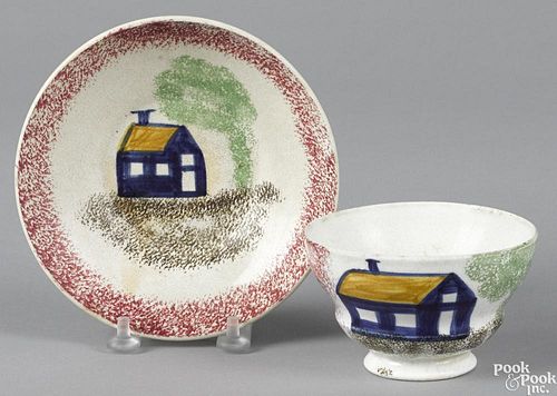 Red spatter cup and saucer with blue schoolhouse decoration.