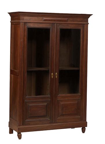 French Art Deco Carved Walnut Bookcase, c. 1940, the stepped crown over double doors with upper glazed panels over lower fielded wood panels, flanked 