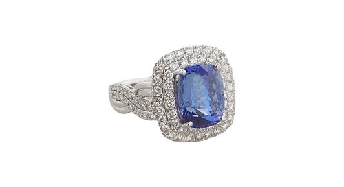 Lady's Platinum Dinner RIng, with a 5.1 carat cushion cut tanzanite atop a graduated concentric border of tiny round diamonds, the pierced bypass shou