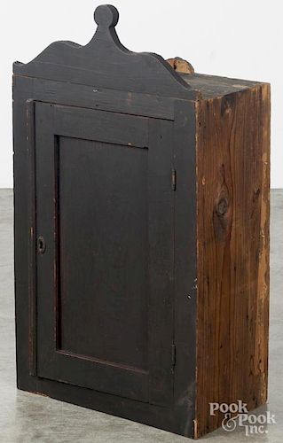 Stained pine hanging cupboard, 19th c., with a lollipop crest and paneled door