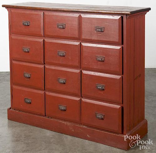 Painted pine apothecary cupboard, early 20th c., with a later red surface, having twelve drawers