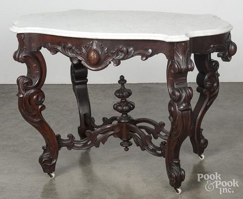 Victorian marble top center table, late 19th c., with a turtle-shaped top, a carved apron, and legs