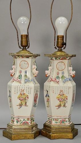 Pair of famille rose porcelain urns having hexagon body with painted panels of Guanyin and scholars, molded foo dog handles, and dra...