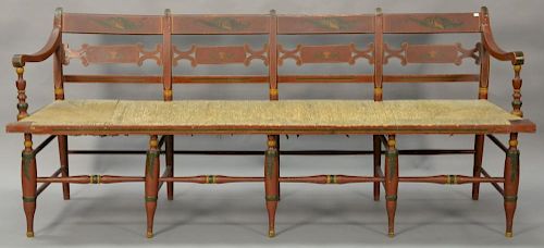 Windsor bench with thumb back and rush seat on turned legs, having old red paint with stenciling, circa 1840. ht. 32 1/2in., seat ht...