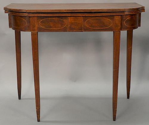 Federal mahogany games table having D shaped top over conforming frieze with oval panel inlays, all set on square tapered legs, circ...