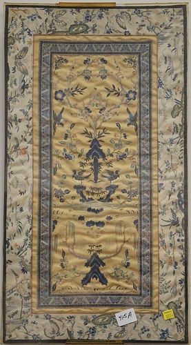 Two Oriental silk panels including one embroidered blossoming tree and birds and the other a Guanyin in a courtyard with scrolling p...