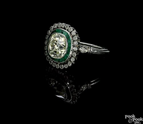 Platinum, emerald, and diamond ring, ca. 1920, with an Old Mine cut central, cushion shape