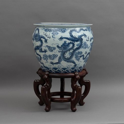 MACETERO. CHINA, SXX. Elaborado en porcelana.Decorado con dragones y motivos orgánicos en azul. Con base de madera. Detalles de conserv